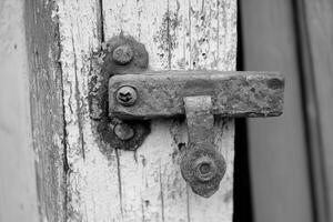 Close-up of a rusty door latch on weathered wood. photo
