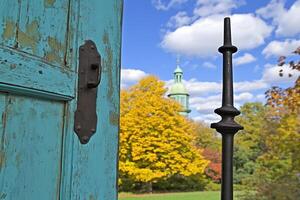 A weathered doorframe with a view of a church and trees. photo
