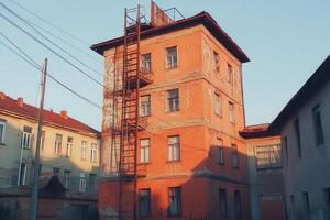 A weathered orange building with a fire escape. photo