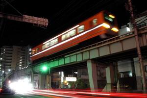 Nighttime urban scene with a moving train above. photo