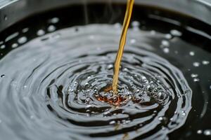 Liquid being poured into dark, rippling water surface. photo