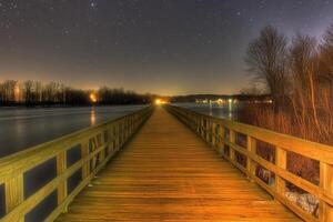 Night view of a wooden pier extending over water. photo