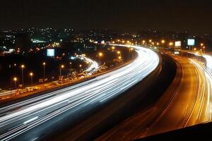 Nighttime highway with light trails and city skyline. photo