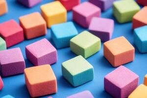 Colorful foam cubes scattered on a blue surface. photo