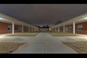 Nighttime view of a school courtyard with brick buildings. photo