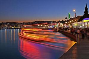 Night scene of a harbor with colorful lights and a boat. photo