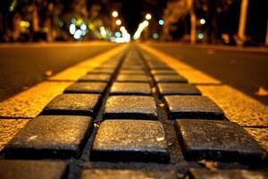 Nighttime view of cobblestone street with yellow lines. photo