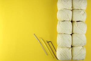 On a yellow background there is yarn and knitting accessories photo
