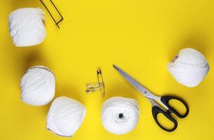 White yarn and knitting accessories lie on a yellow background. photo