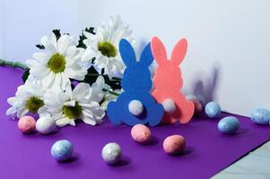 Easter decoration with eggs, rabbits and daisies on a purple background photo