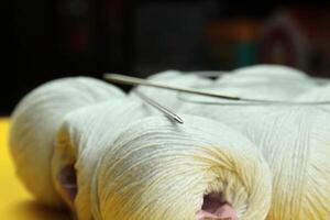 Close-up of knitting needles lying on white yarn. Macro shot photo
