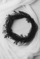 Wreath of black leaves on tulle against light backdrop photo