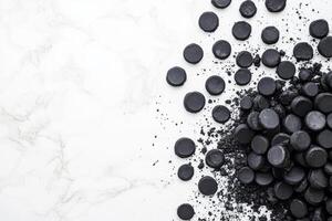 Activated charcoal pills and powder on white marble photo