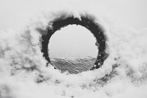 Snow covered circular opening in monochrome winter scene photo
