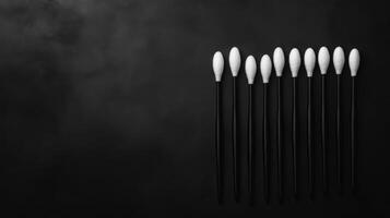 Row of white cotton swabs on black photo