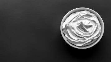 Bowl of whipped cream on dark background, simple dessert photo