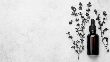 Dark Glass Dropper Bottle with Branches on Marble Surface photo