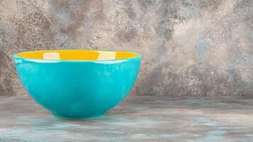 Vibrant Blue and Yellow Ceramic Bowl on Rustic Grey Surface photo