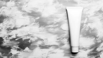 Minimalistic white cosmetic tube on a grey textured surface photo