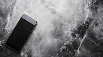 Black smartphone lying on a textured marble surface photo