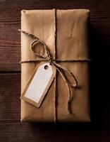 Present Wrapped in Brown Paper With Twine on Wooden Table Ready for Gifting photo