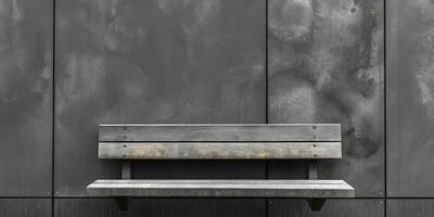 A solitary wooden bench against a textured gray wall, evoking a sense of minimalist serenity. photo