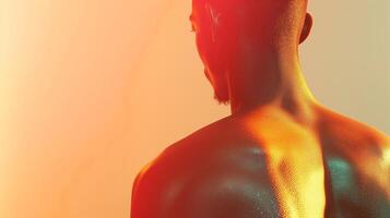 A male subject with dark skin showcases a glistening back, illuminated by vibrant orange and yellow hues, creating an artistic ambiance. photo