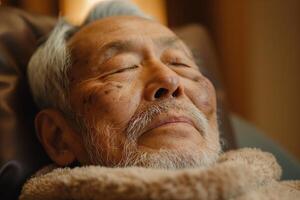 Close-up of an elderly Asian man peacefully relaxing with eyes closed in a cozy environment. photo