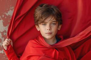 A young Caucasian boy with expressive green eyes, draped in a vibrant red fabric, exudes a sense of wonder and curiosity. photo
