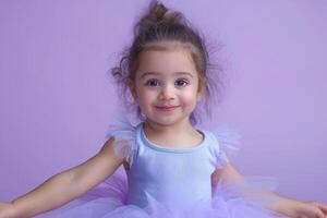 A joyful young girl in a light blue tutu smiles brightly against a soft purple background. photo