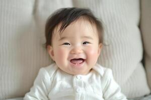 Adorable baby boy with expressive smile, wearing a cozy white outfit, exuding happiness against a soft, neutral background. photo