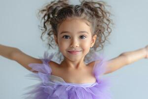 A joyful Hispanic girl in a purple tutu poses with arms wide open, expressing happiness and innocence. photo
