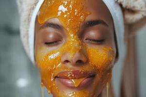 A young woman of mixed ethnicity relaxes with a honey mask on her face, showcasing radiant skin and a serene expression. photo