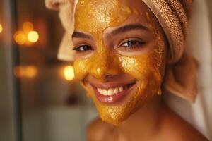 Smiling young woman with a honey face mask, wrapped in a towel, enjoying a spa day at home. photo