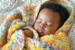 A peaceful baby boy of African descent peacefully sleeping wrapped in a colorful knitted blanket. photo