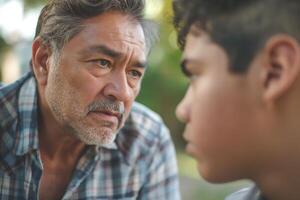 An intense conversation between an older Hispanic man and a young boy in a thoughtful moment outdoors. photo