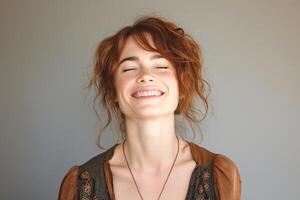 A joyful young Caucasian woman with curly red hair, smiling warmly against a neutral background. photo