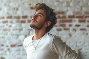 A young Middle-Eastern man with curly hair gazes upward, embodying a sense of contemplation and hope against a rustic backdrop. photo