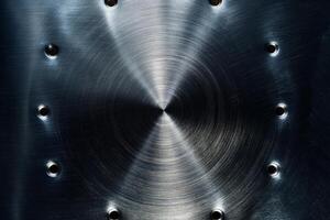 Close-up view of textured metal surface with a central circular pattern and evenly spaced holes, showcasing a modern industrial aesthetic. photo