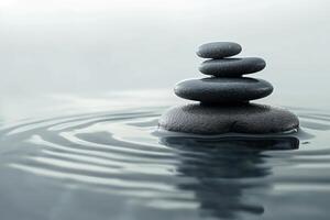 A serene stack of smooth black stones balanced on the surface of gently rippling water, creating a peaceful atmosphere. photo