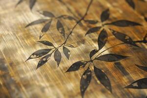 An intricate design featuring black leaves on a shimmering golden surface, creating a blend of nature and elegance. photo