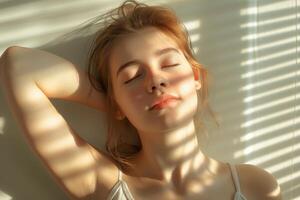 A serene young Caucasian woman relaxing with her eyes closed, bathed in soft sunlight and shadow patterns. photo