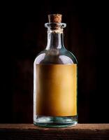 Glass Bottle With Blank Label Sitting on Wooden Surface Illuminated by Soft Light photo