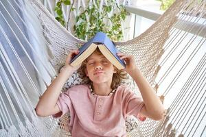 Boy with book on head lying in hammock photo