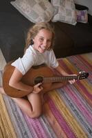 Positive kid sitting on floor and playing guitar photo