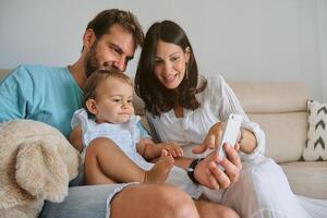 Happy family using smartphone on sofa photo