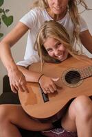 Blonde girl looking at camera while playing guitar photo