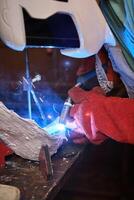 Manual worker using welding torch at factory photo