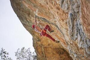 Faceless strong climber holding onto rock while hanging on rope photo