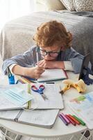 Adorable boy taking notes in notebook at home photo